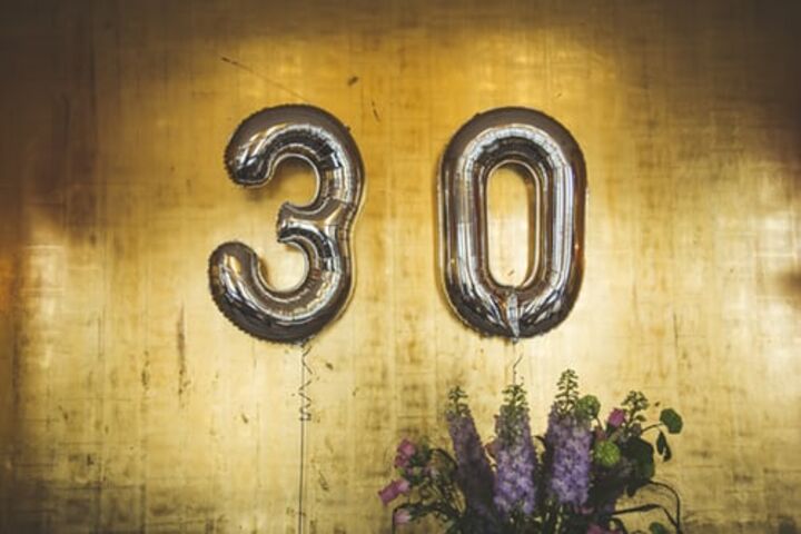 Silver number balloons that say 30 against a gold background.