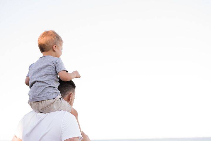A man with a small child on his shoulders looking away from the camera.