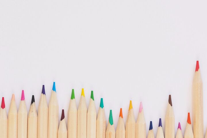 A series of freshly sharpened multi-colored pencils lined up together on a light background.