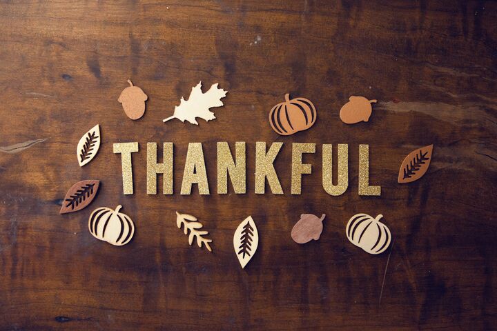 The word “Thankful” in gold lettering circled by fall leaves.