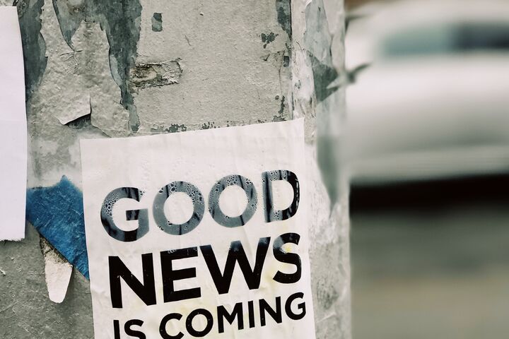 A sign on a street pole that reads, “good news is coming.”