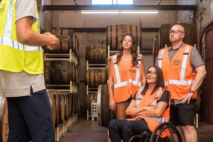 Workers in a brewery wearing safety vests having a discussion