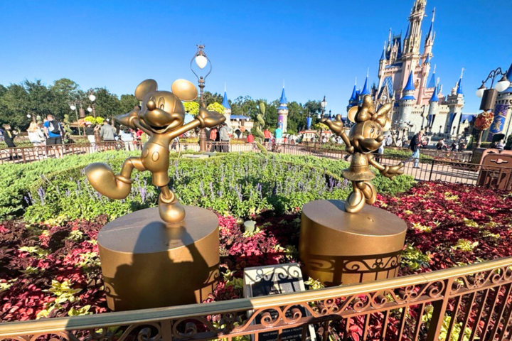 a bright sunny day at Disney World with two gold statues, one of Mickey Mouse and Minnie Mouse