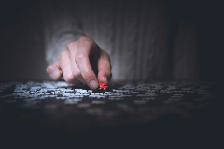 a hand that is holding a red puzzle piece with all white pieces on the table