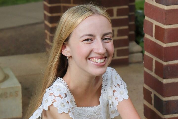 Sarah Todd Hammer smiles as she sits with her arms crossed. 