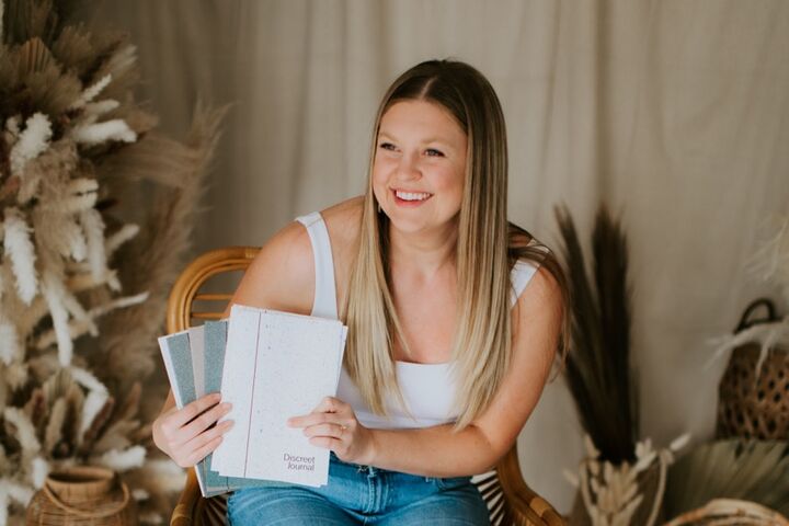 Sommer Fox sits on a chair while showcasing her Discreet Journals.