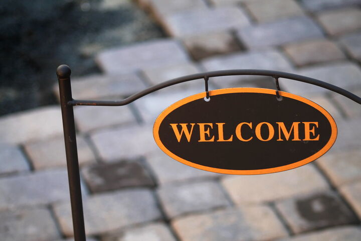 an oval black sign with gold letters stating "WELCOME"