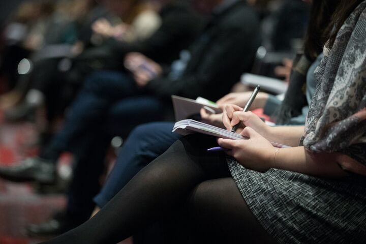 a close up of people taking notes in their notebook at a conference