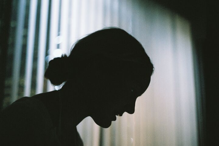 a shadow figure of a woman's face looking down at the floor