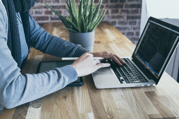 A person works on their laptop computer at their desk.