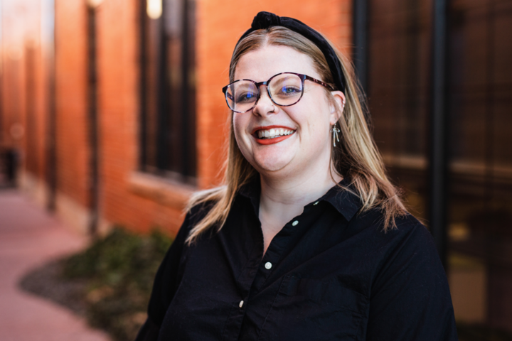 Sheridan Powell wears a black headband and black framed glasses.