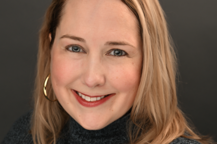 Katherine Macfarlane wears a mock gray turtleneck with her hair down.