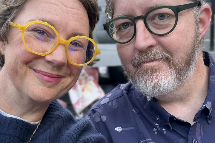 Alma and Mike Loveland wear colorful glasses and blue shirts.