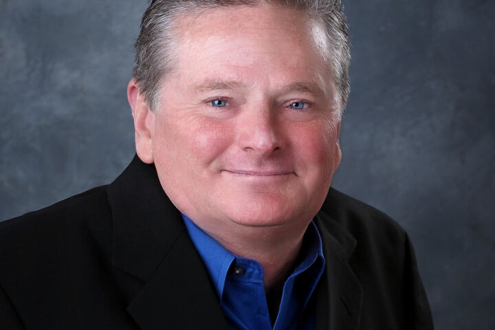 Sam Schmidt wears a royal blue button down shirt and black blazer.