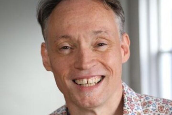 Lawrence Carter-Long smiles while wearing a floral shirt.