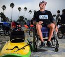 Charles Webb in his wheelchair next to an adaptive surfboard.