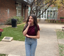 Delila Vasquez stands with an arm crossed, the other at a fist that rests on her chin.