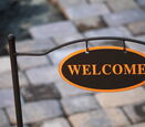 an oval black sign with gold letters stating "WELCOME"