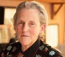 Temple Grandin wears a colorful floral embroidered top and monogrammed tie.