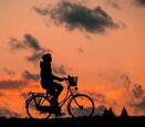 Silhouette of a person on a bike, with a sunset background. 