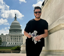 Jordan Burk holds a koala bear puppet in front of the U.S. Capitol Building.