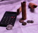 A calculator next to some pennies and coins on a table. 
