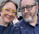 Alma and Mike Loveland wear colorful glasses and blue shirts.