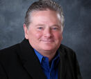 Sam Schmidt wears a royal blue button down shirt and black blazer.